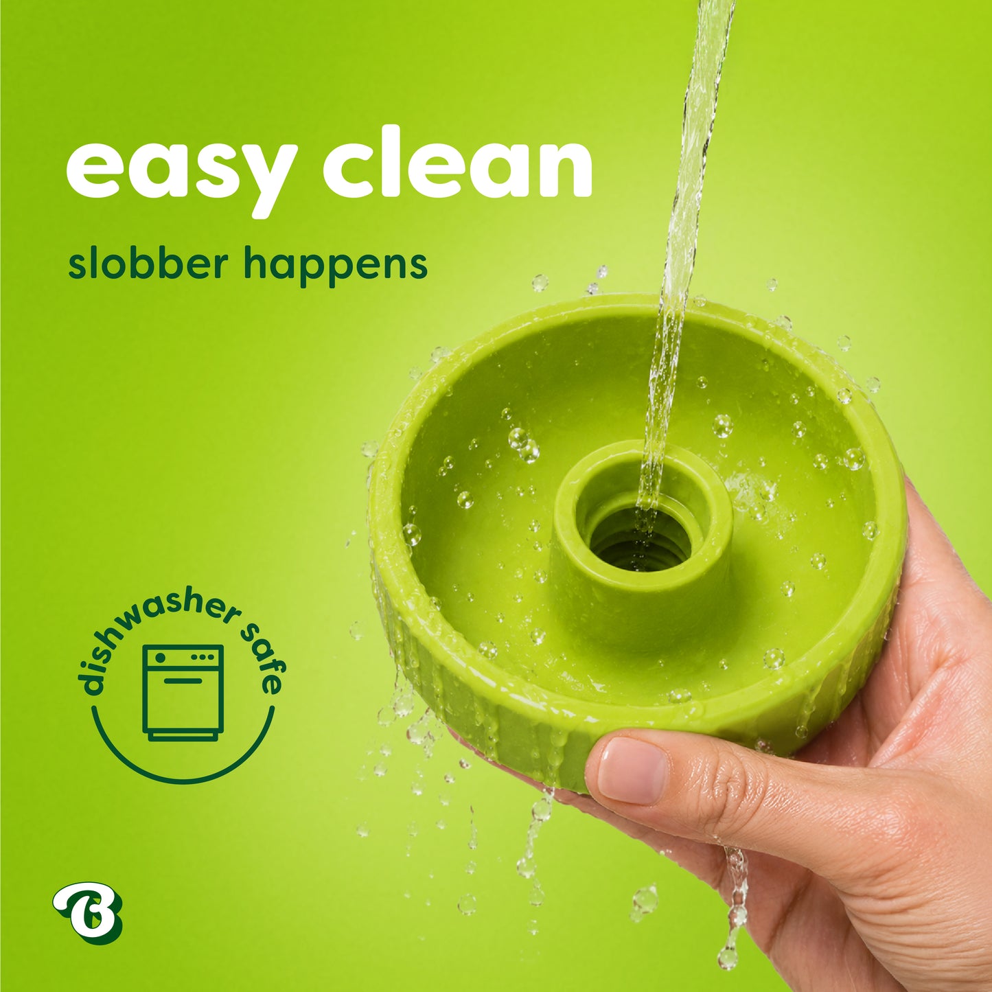 A hand holds a green Benebone Tongue Twister natural rubber puzzle toy under running water. Text reads easy clean, slobber happens and a dishwasher safe icon is shown. Perfect for dog enrichment, the background is bright green.