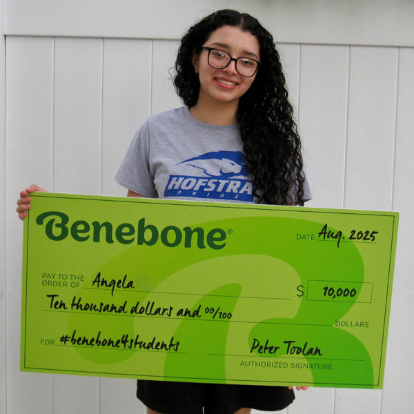 Benebone scholarship winner Angela holding a large green check against a white background.