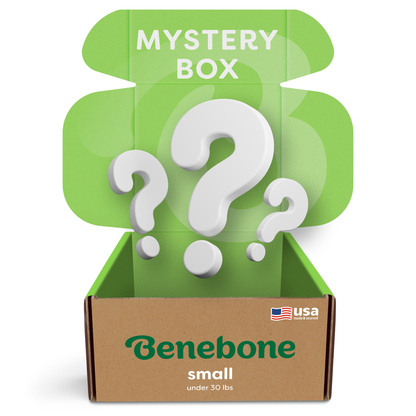 A green and brown Benebone Mystery Box for small dogs under 30 lbs is open, showing "MYSTERY BOX" with big white question marks inside. A small USA flag logo hints at surprise durable dog toys from Benebone.