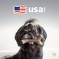 A small black dog with long hair holds a bone-shaped toy from Benebone’s Limited Edition Chew Collection (4-Pack). The background features a stylized American flag, “usa made,” and a small green logo in the bottom right.