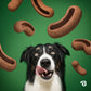A black and white dog licks its lips as Benebone Treat Pod for Tongue Twister brown, curved peanut butter dog treats float around it on a green background.