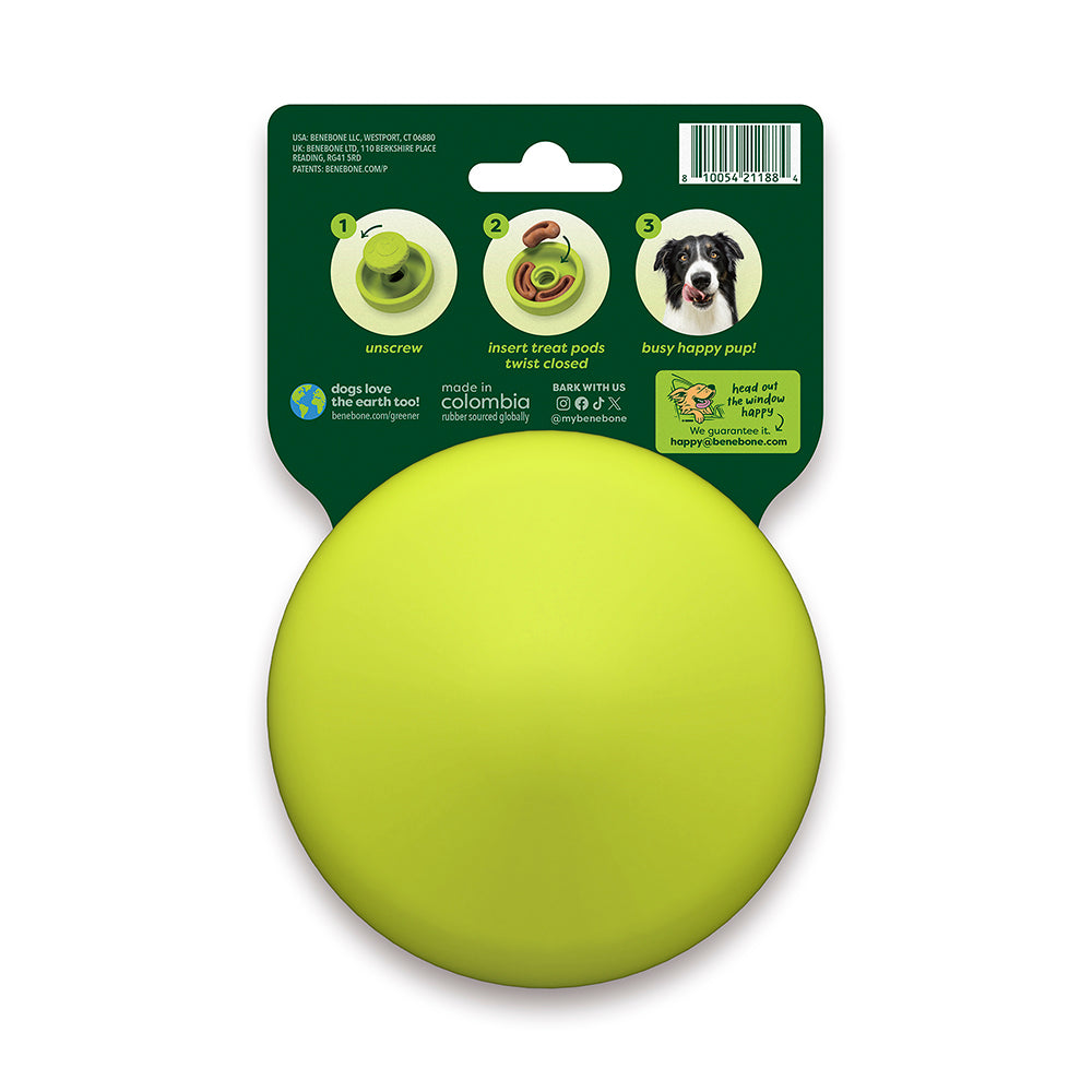 A yellow, round dog toy called the "Tongue Twister" by Benebone comes in packaging with instructions on how to unscrew it and insert treats. The packaging features a photo of a happy dog and text that highlights how it keeps dogs busy and happy. The Tongue Twister toy is made in Colombia.