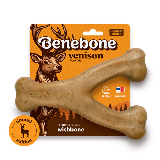 The Benebone Venison Wishbone is a durable, wishbone-shaped dog toy flavored with venison. It comes in orange packaging decorated with a deer illustration, limited edition labels, and icons that highlight its durability and USA-made quality.